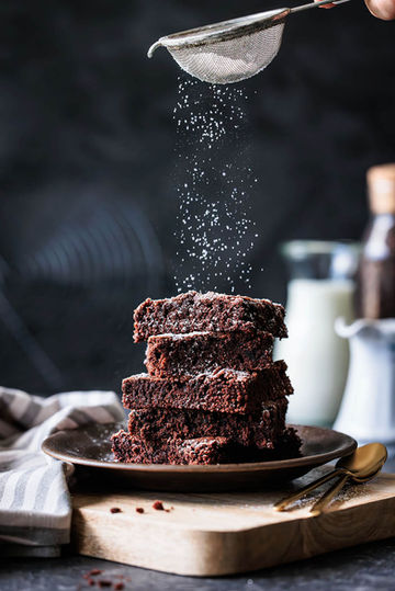 gestapelte saftige Brownies die mit Puderzucker bestreut werden