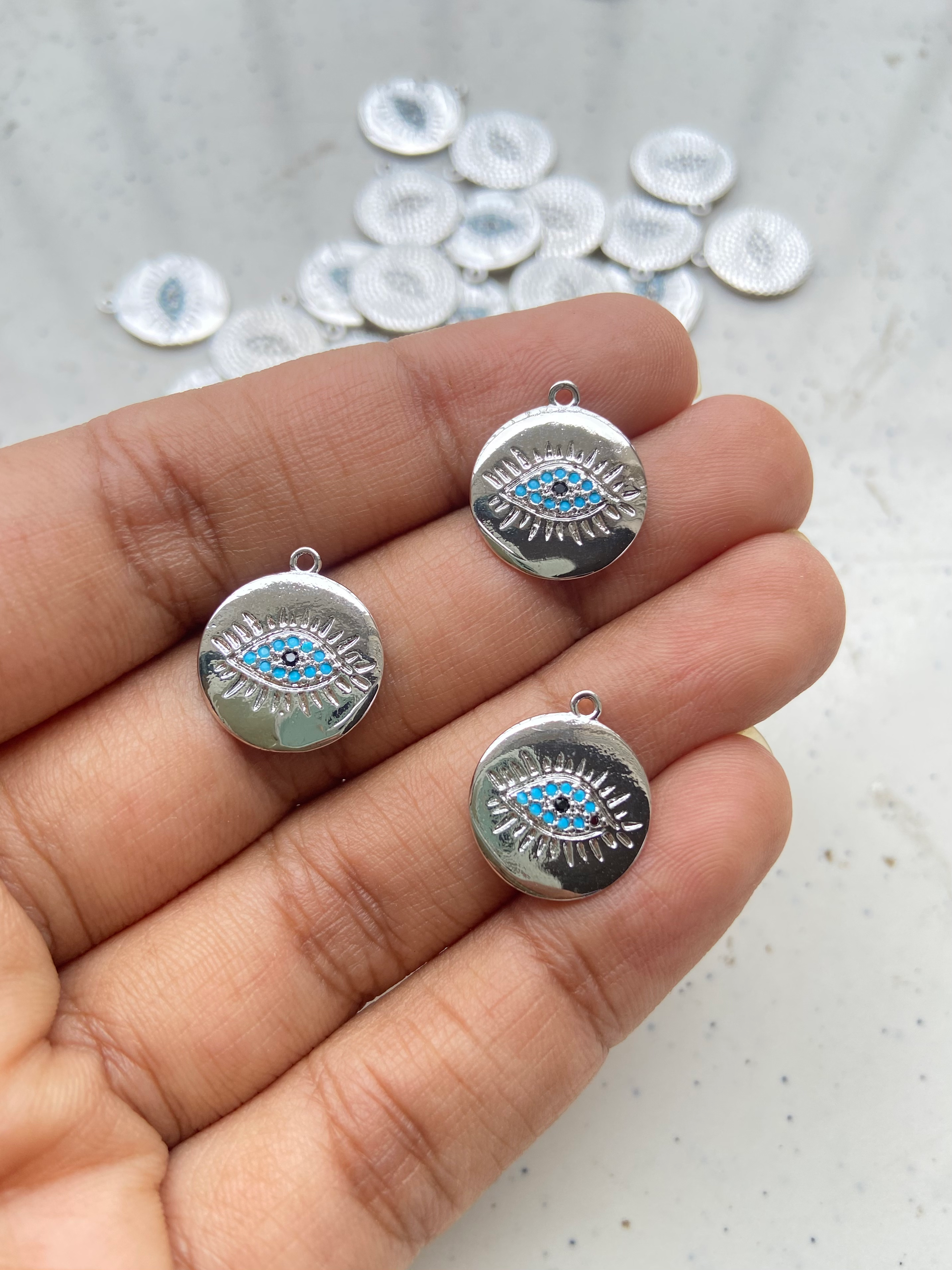 Platinum plated flat round charm with zircon evil eye