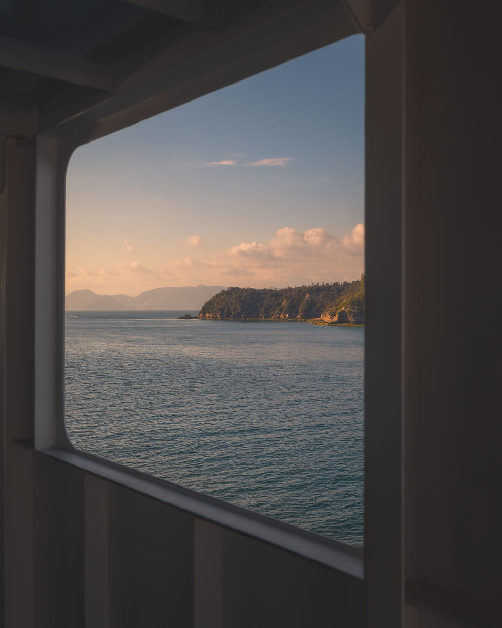 View of the Seto Inland Sea and islands at sunset seen from a ferry window in Japan