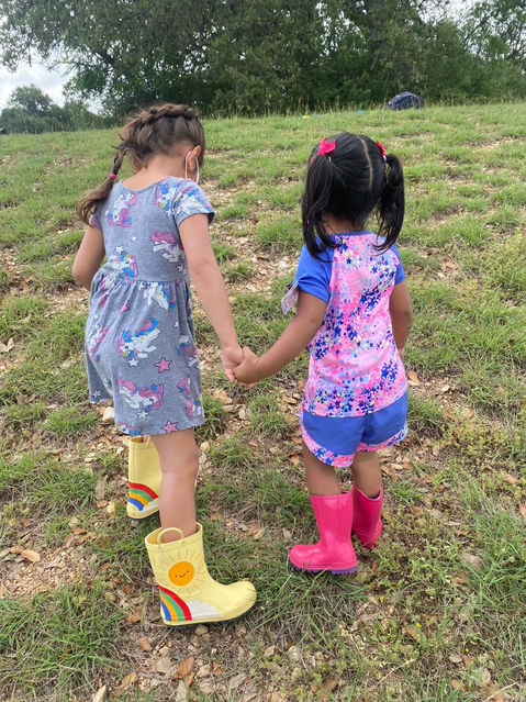 Little girls holding hands in rain boots