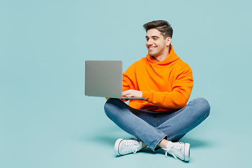 Full body young IT man he wearing orange hoody casual clothes sitting hold use work on lap