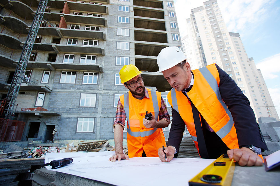 Twee mannen hangen boven de bouwtekiningen van een flat in een contsructiegebied