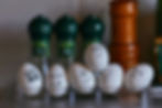 Eggs with drawn faces showing various emotions in a carton. Green spice containers in background. Humorous and playful mood.