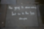 White chalk text on wet gray pavement reads: "The grief is never ending but so is the love. @losinglxve." The mood is reflective.