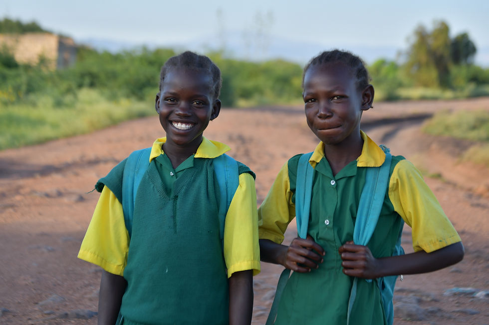 Two smiling schoolgirls in green and yellow uniforms.