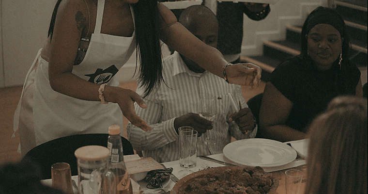 Chef serving dishes at a communal dining event featuring South African flavours and modern presentation.