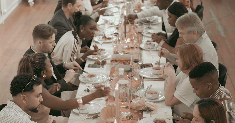 Warm, candlelit long‑table dining scene highlighting connection and shared culinary experiences.