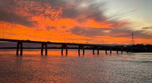 “Pier stretching over calm ocean water during a vibrant orange sunset.”