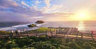 “Scenic coastal lookout with ocean waves under colorful evening sky.”