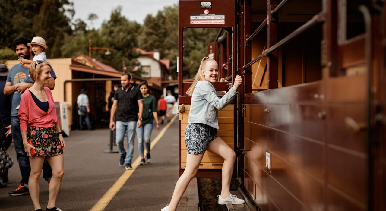 “Visitors boarding vintage steam train at a rural station.”
