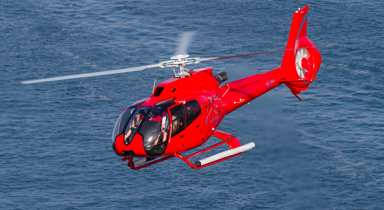Helicopter flying over the ocean with passengers enjoying an aerial reef view