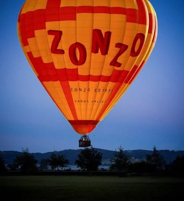 Hot air balloon rising over countryside during sunrise in Melbourne, Australia.