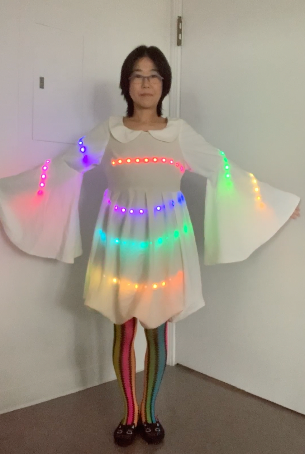 Full view of the LED dress in daylight; sensors on the dress activate lights through handshakes and interactions. [Watch video to see the performance in action].