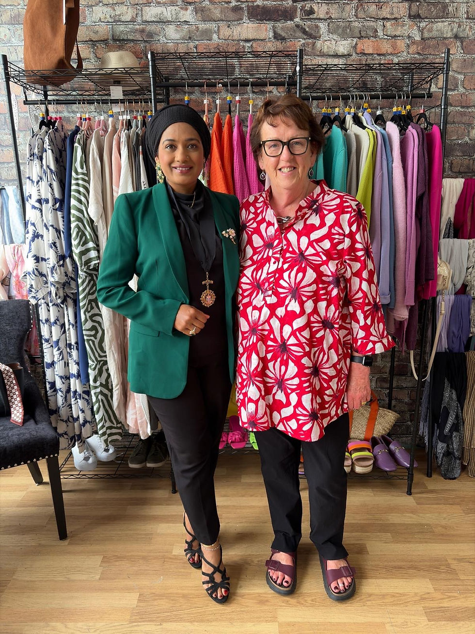 Two women standing and smiling in a community clothing shop