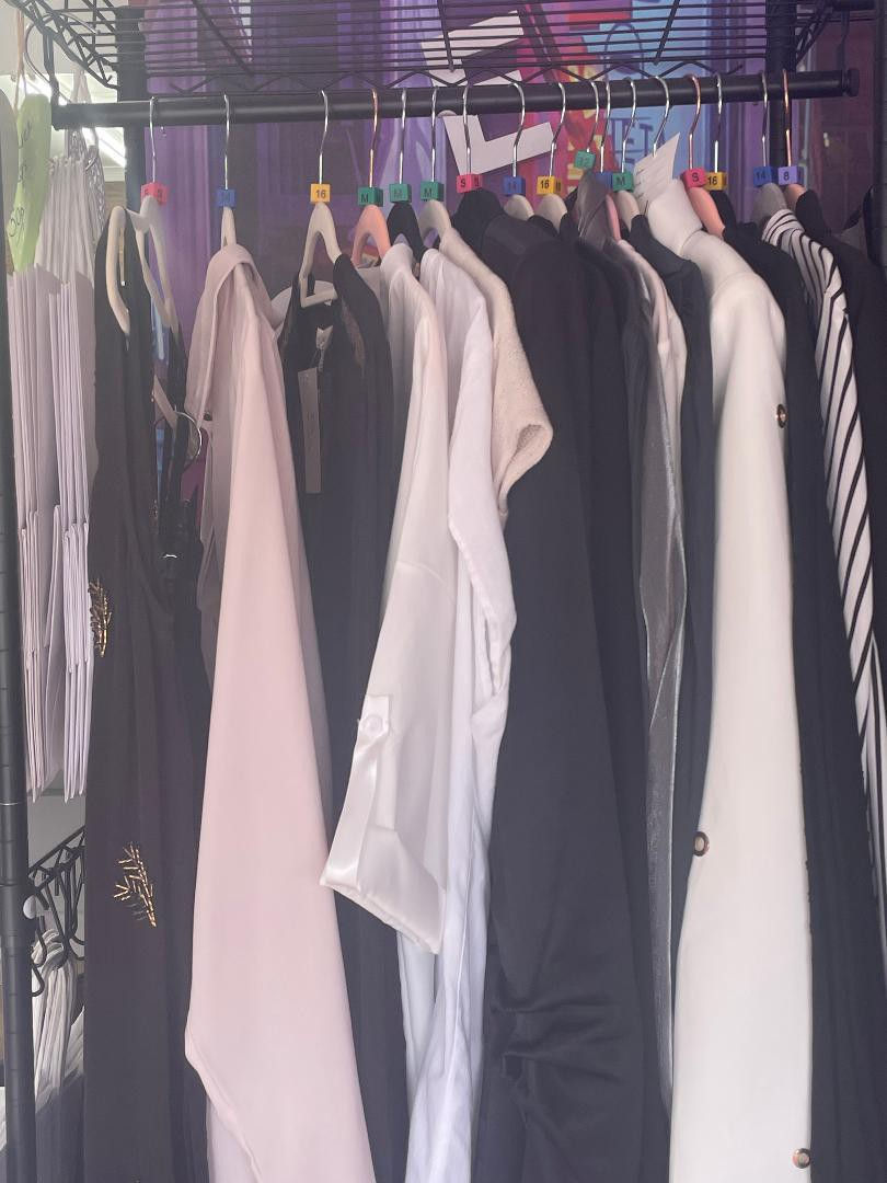 portrait photo of a rail of ladies clothing in various neutral colors, dominant colors black white beige