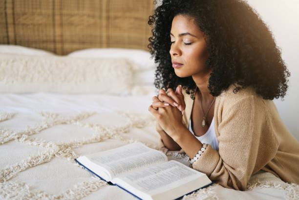 Young African American woman praying with her Bible, seeking guidance and faith