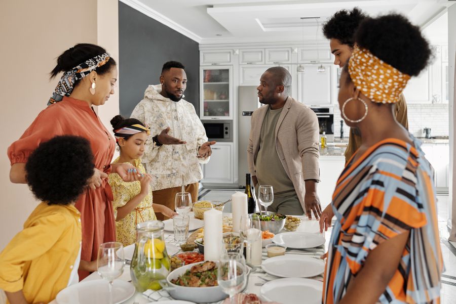 African American family gathered around the dinner table together, sharing a meal and conversation