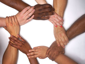 Hands of black and white people forming a circle of racial harmony.