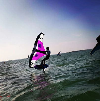 Une personne debout sur une planche en train de naviguer en wingfoil sur le Golfe du Morbihan