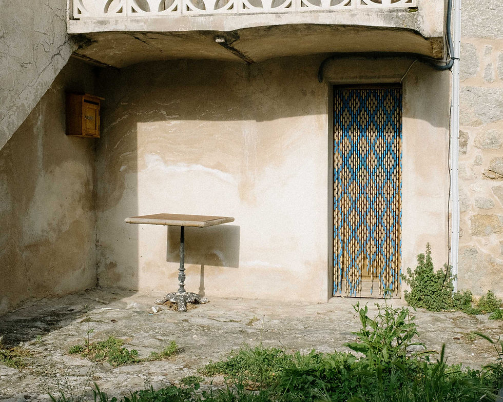 Terrace with wooden table and beaded curtain with crisscross pattern.