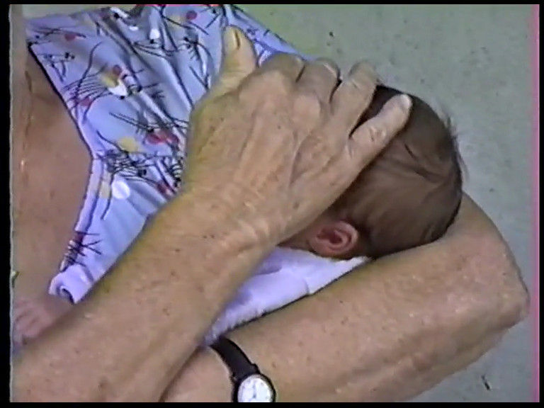 Hand placed on the head of a newborn baby in her arms