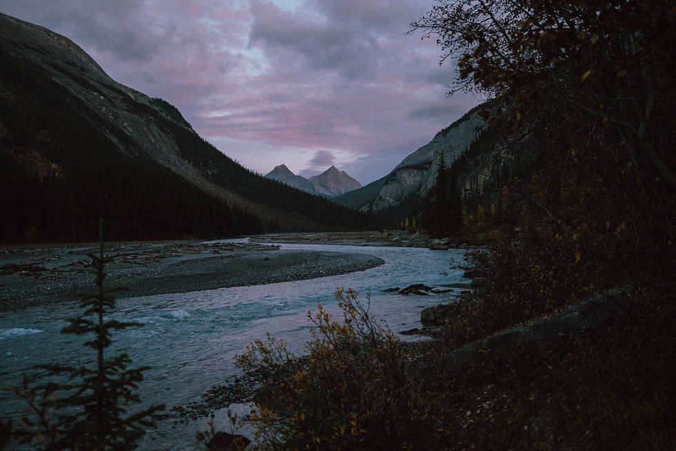River flowing through a mountain valley at dusk.