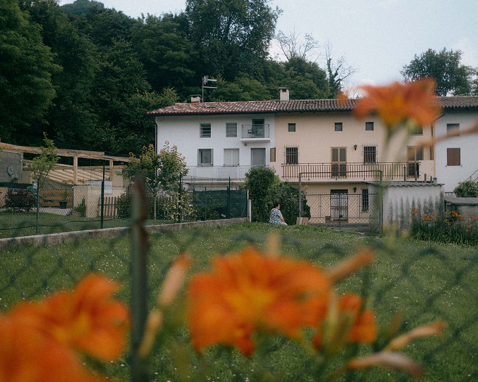 Woman in front of a country house with orange flowers in the foreground.