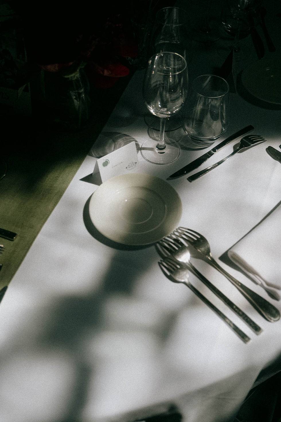 Detail of a wedding place setting on a white tablecloth and green placemat.