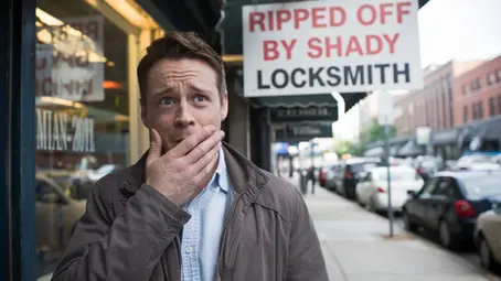 Man looks worried with hand on mouth in city street. Sign reads "Ripped Off by Shady Locksmith" in bold red and black text.