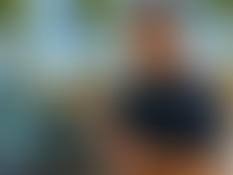 A professional automotive locksmith programming a modern car key fob beside a vehicle in a bright South Florida setting, with palm trees and Delray Beach storefronts in the background.