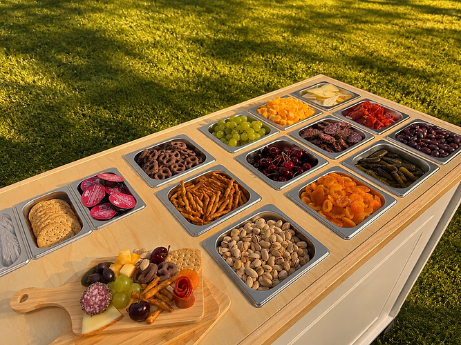 Top of charcuterie cart showing 12 pans with assortment of carcuterie ingredients.
