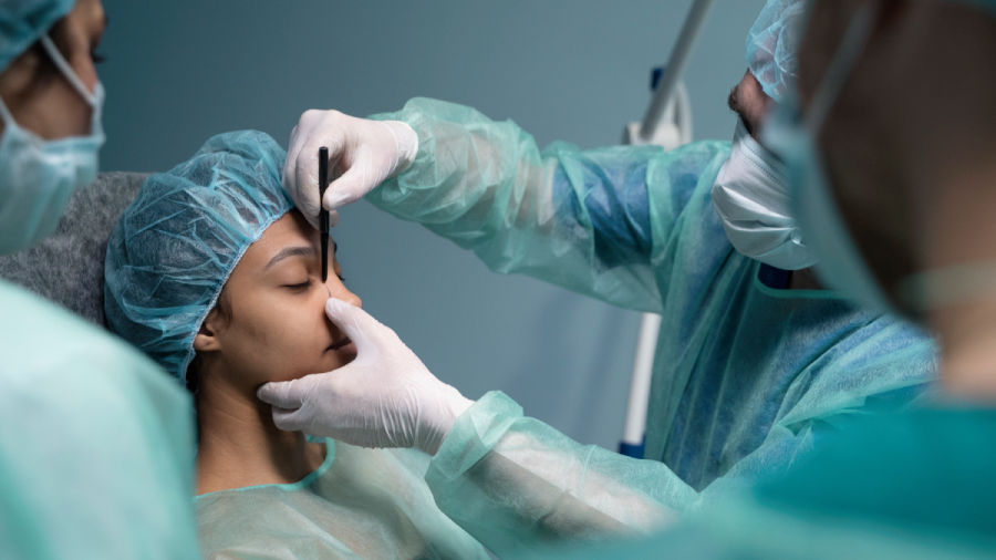 Surgeon marking patient's face before skin tightening surgery in a sterile operating room