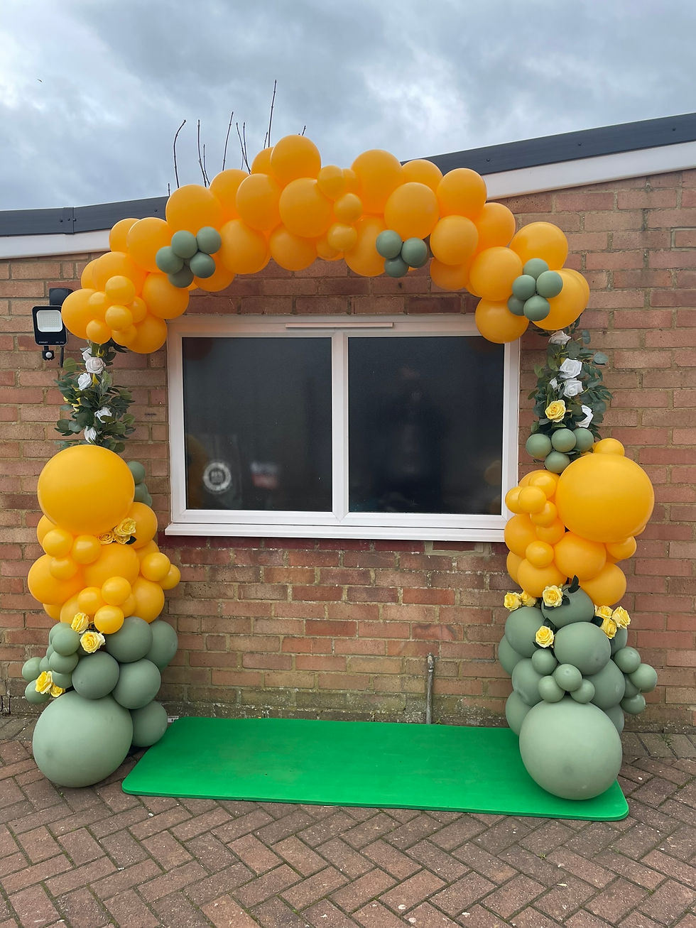 Yellow and sage green organic balloon arch with floral accents for party entrance and event photo backdrop.
