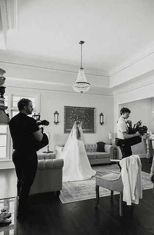 A black and white behind the scenes documentary style photo of a bride and the videographers.