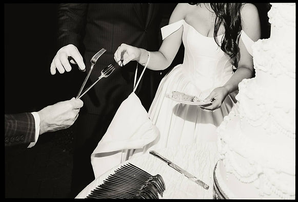 Editorial black and white photo of the bride and groom at their wedding reception enjoying a slice of wedding cake.