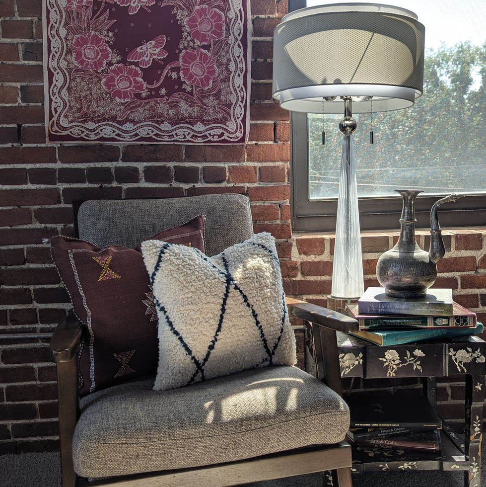Beni Ourain Moroccan wool throw pillow in white with black diamond pattern, styled on a chair with deep red cactus silk pillo