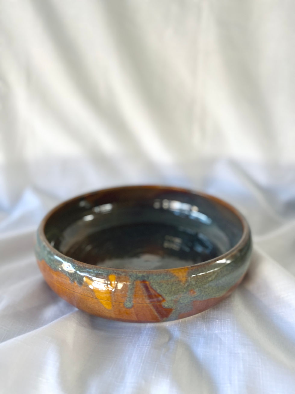 side view of Solstice large serving bowl with tones of blue, purple greens and orange