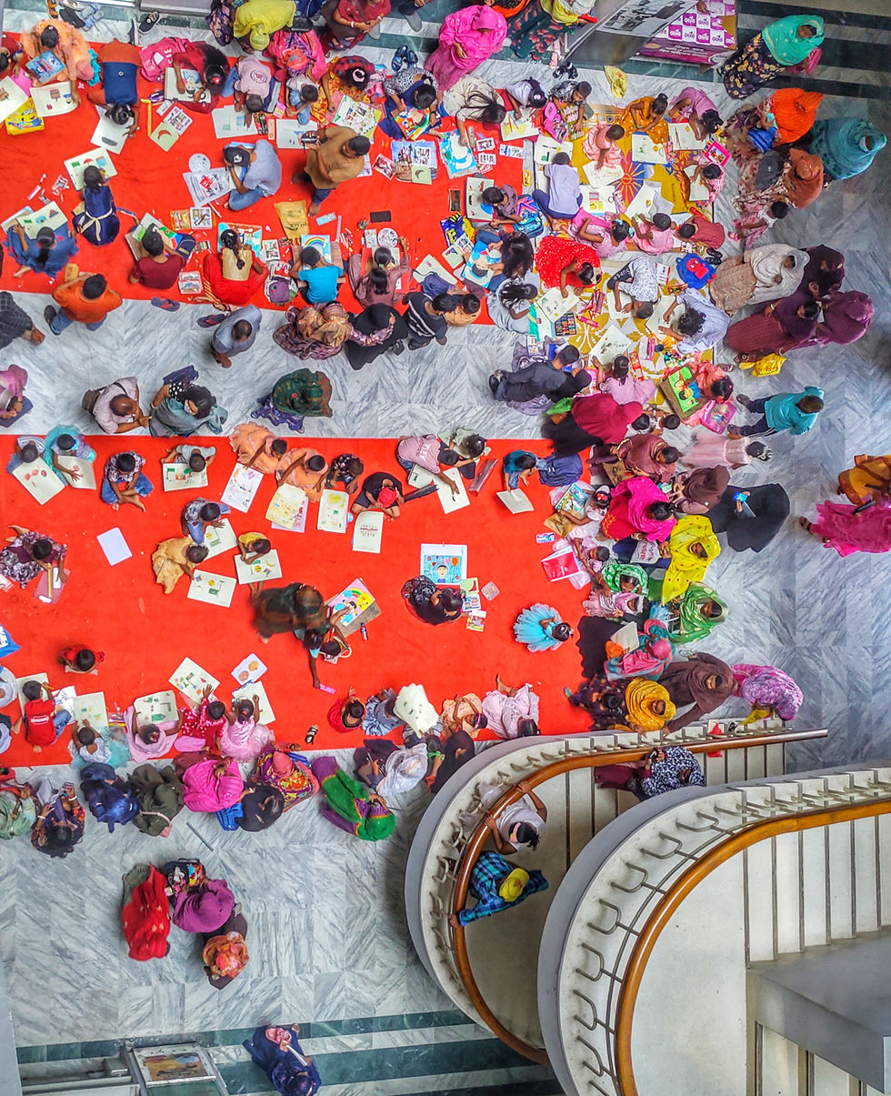 a large group of people are laying on the floor drawing