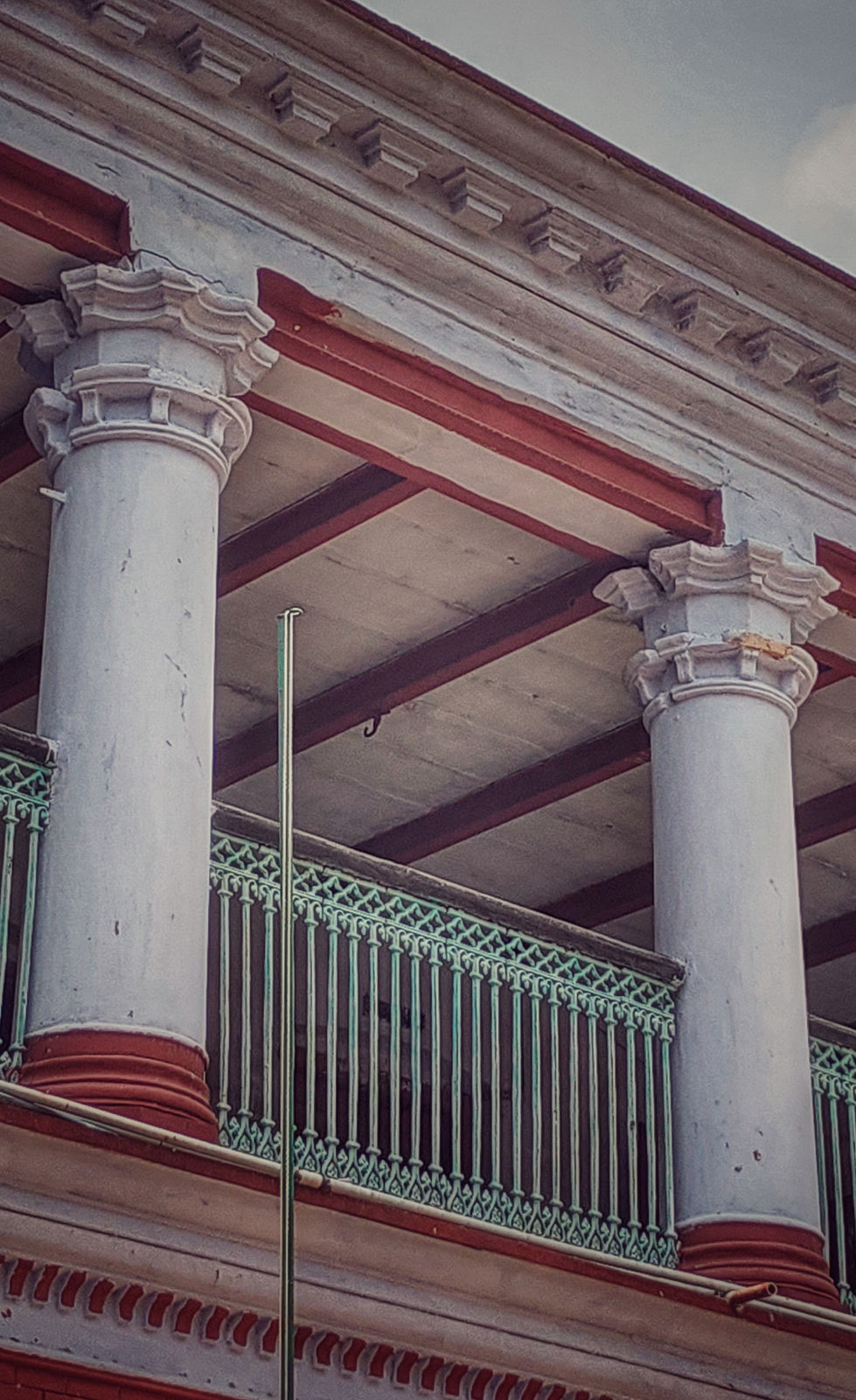 a balcony with columns and a green railing