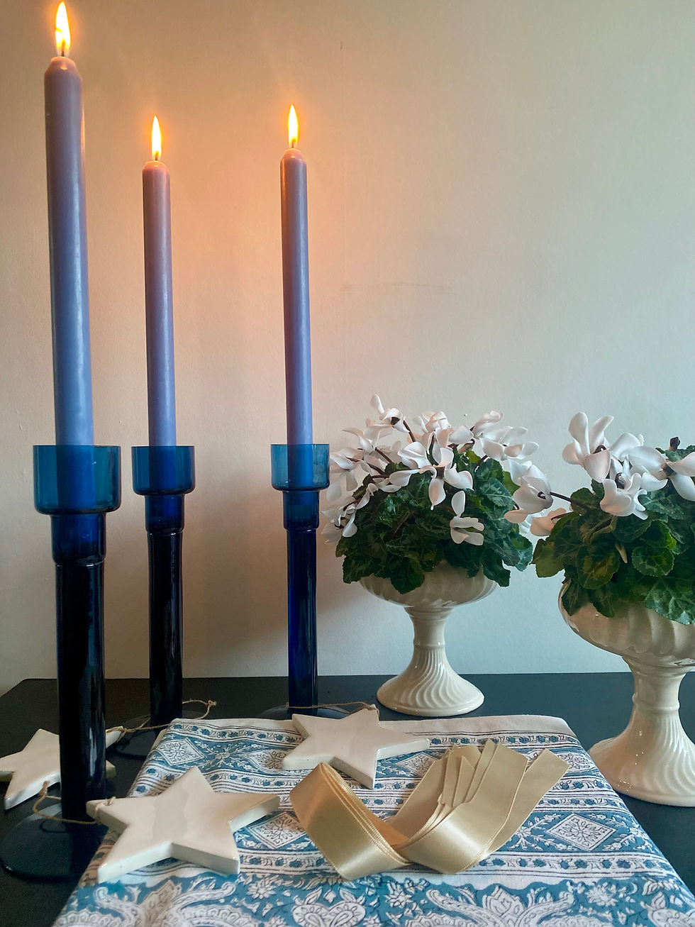 A festive table setting with tall blue dinner candles and white cyclamen in vintage bon bon dishes.