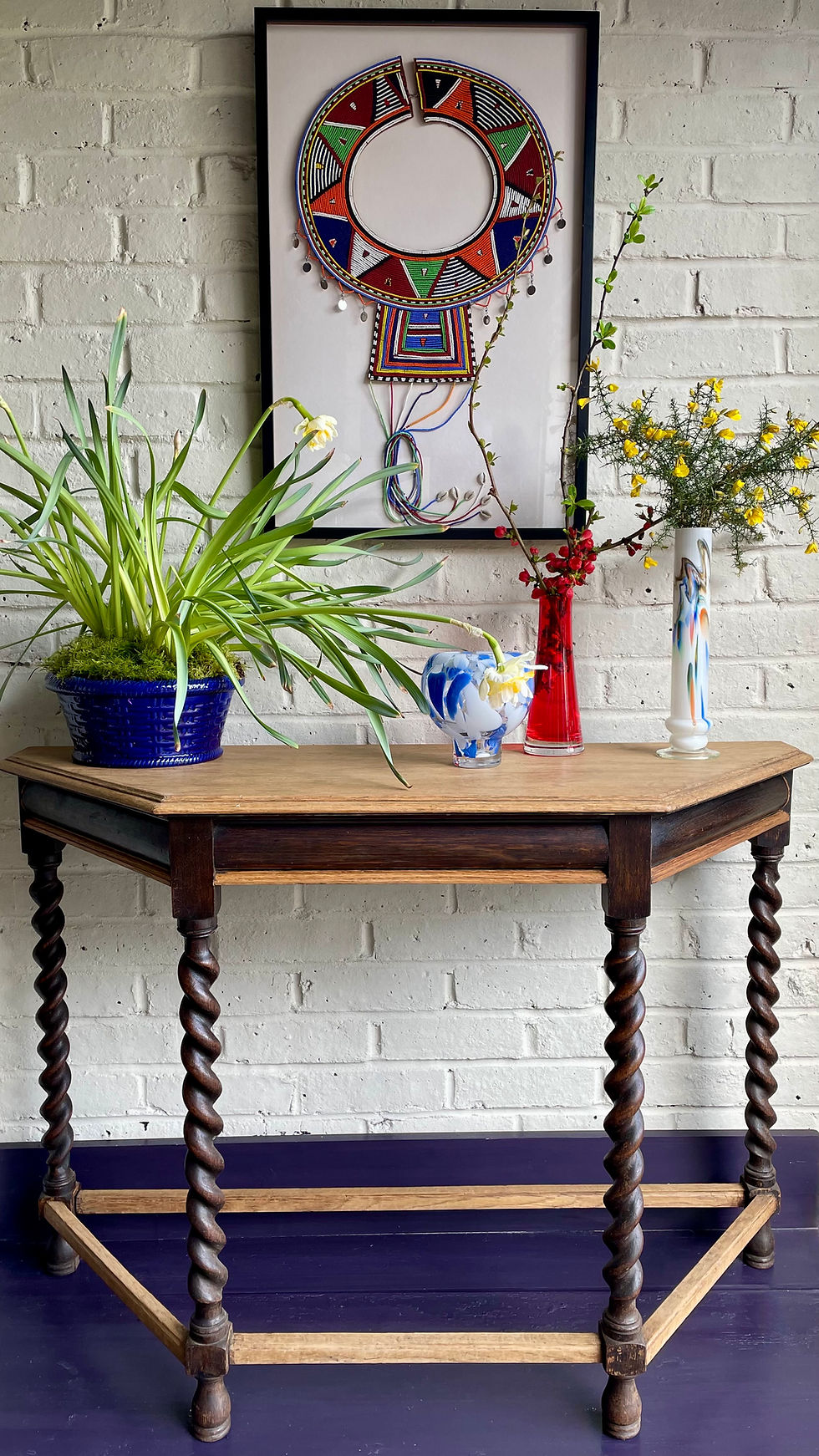 A vintage barleytwist-legged console table styled with vases and planters.