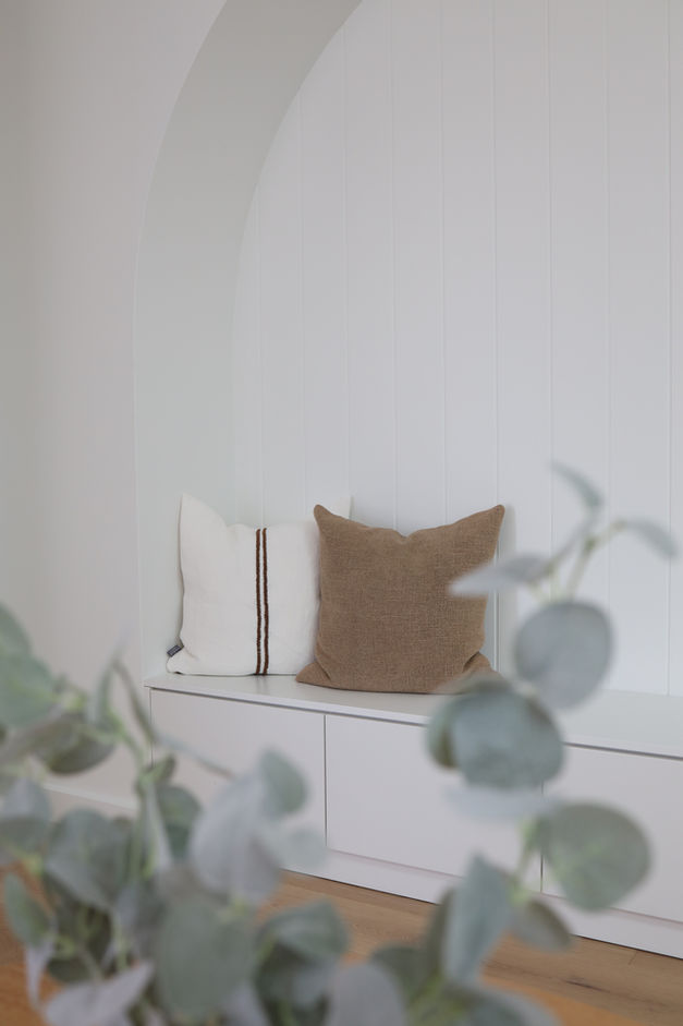 An arched bench seat with VJ panelling, styled with cushions