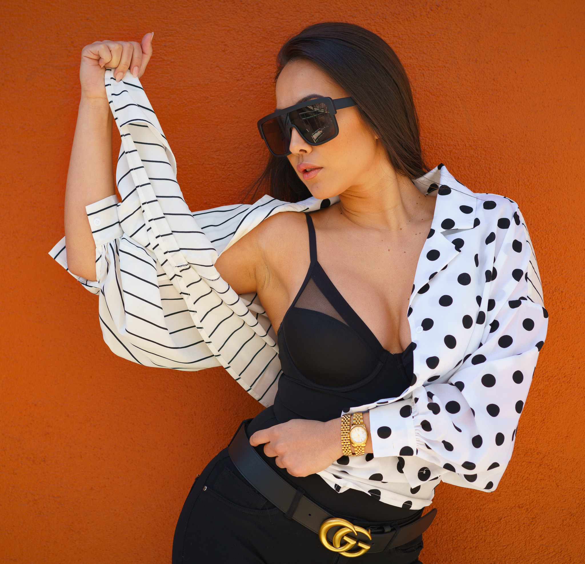 Fashion portrait of a woman against a vivid orange wall.