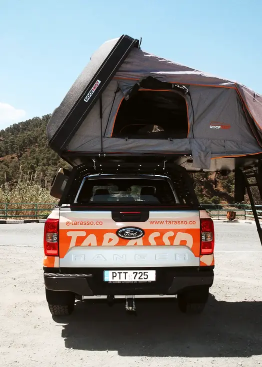 Ford Ranger Camper truck with open rooftop tent back side, and mountains in the background