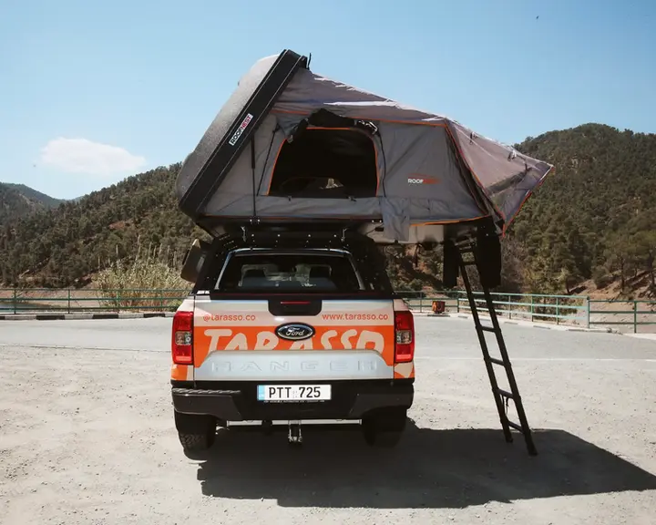 Ford Ranger Camper truck with open rooftop tent back side, and mountains in the background