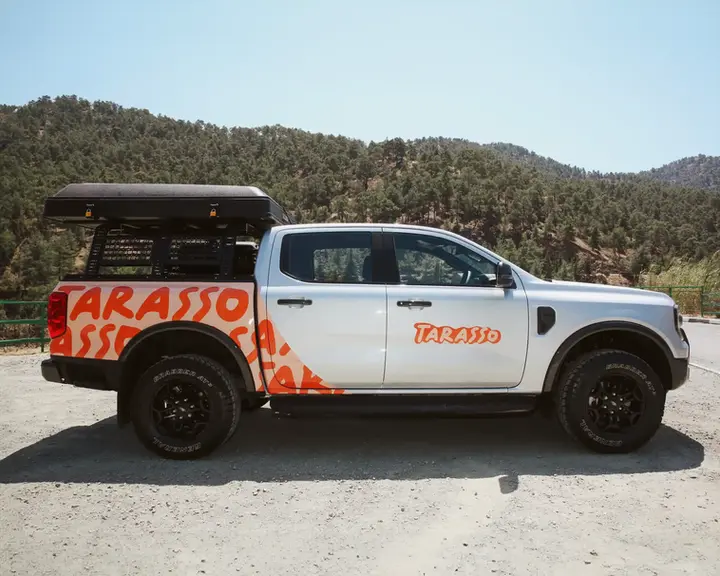 Ford Ranger Camper truck with closed rooftop tent right side, and mountains in the background