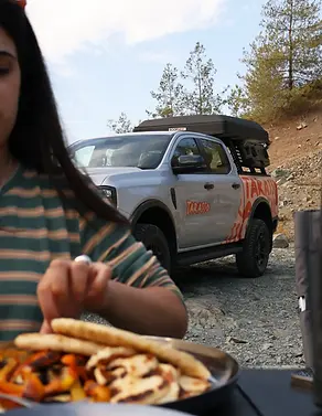 Girl ready to eat her lunch, grilled vegetables, pitta are visible. Ford Ranger Camper Truck is parked just behind her