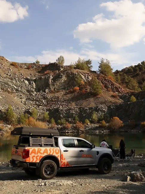 Ford Ranger Camper truck parked next to the lake, with mountains in the background