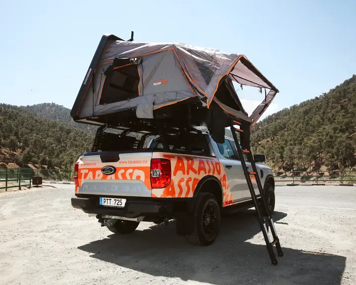 Ford Ranger Camper truck with open rooftop tent back side, and mountains in the background