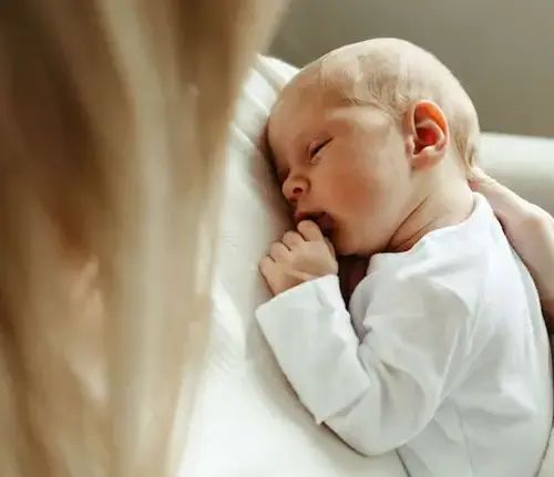 Newborn being cradled by supported birth parent after birth